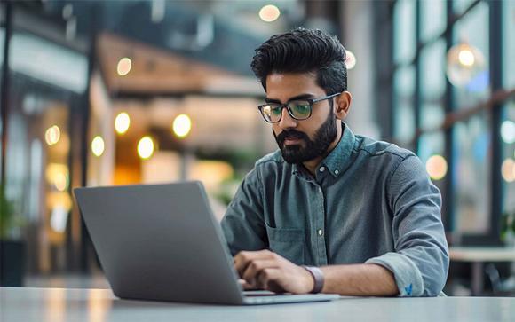 indian man working on laptop in open working space