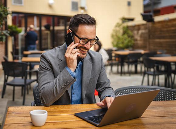 man on phone while working on laptop in cafe