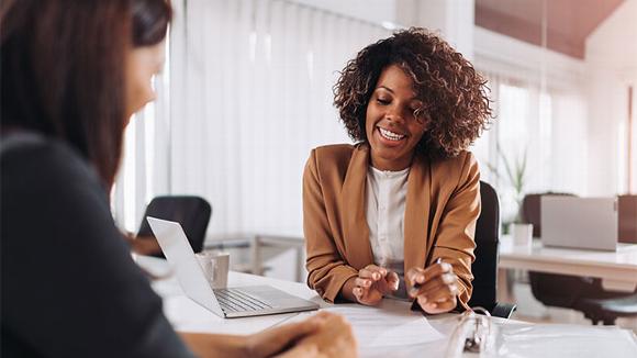 Two women reading over document in office